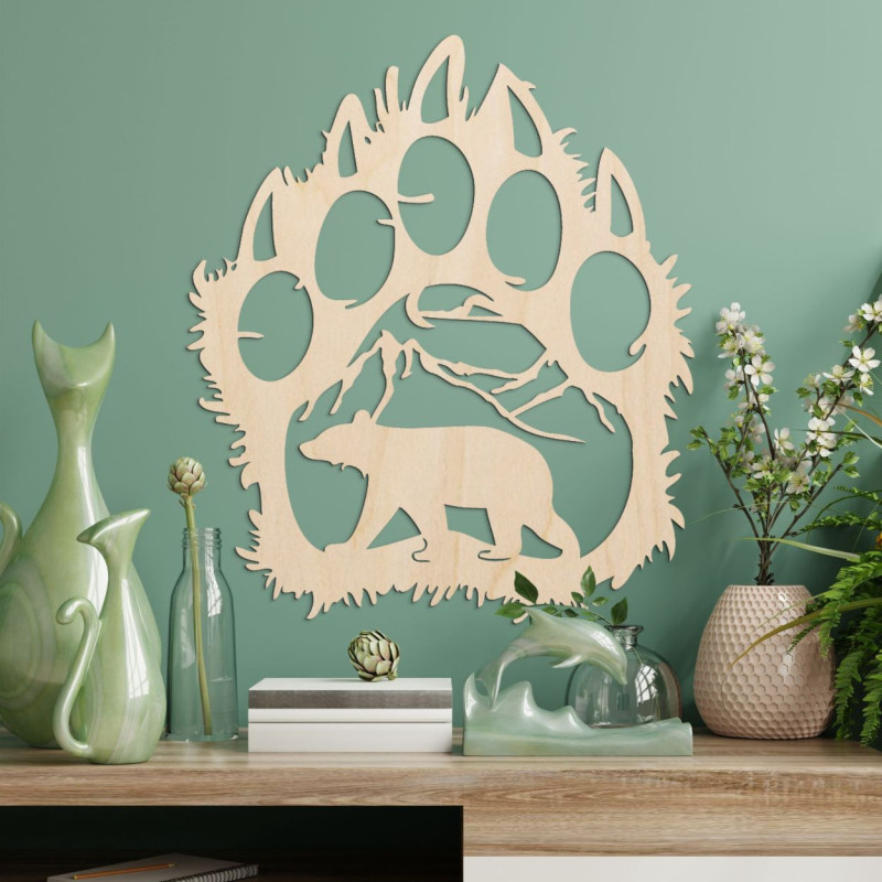 A wooden image of a bear footprint, inside of which is carved the silhouette of a bear walking under the mountains.
