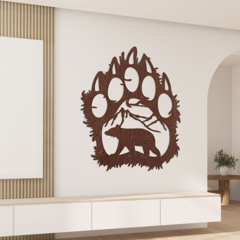 A wooden image of a bear footprint, inside of which is carved the silhouette of a bear walking under the mountains.