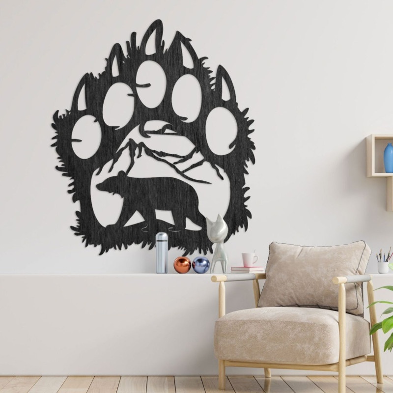 A wooden image of a bear footprint, inside of which is carved the silhouette of a bear walking under the mountains.