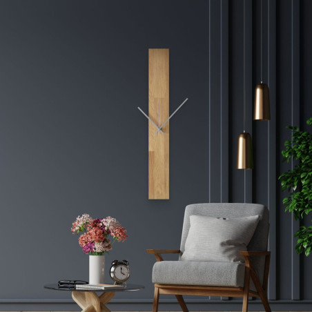 Modern wall clock, glued to a white wall, with simple black hands.