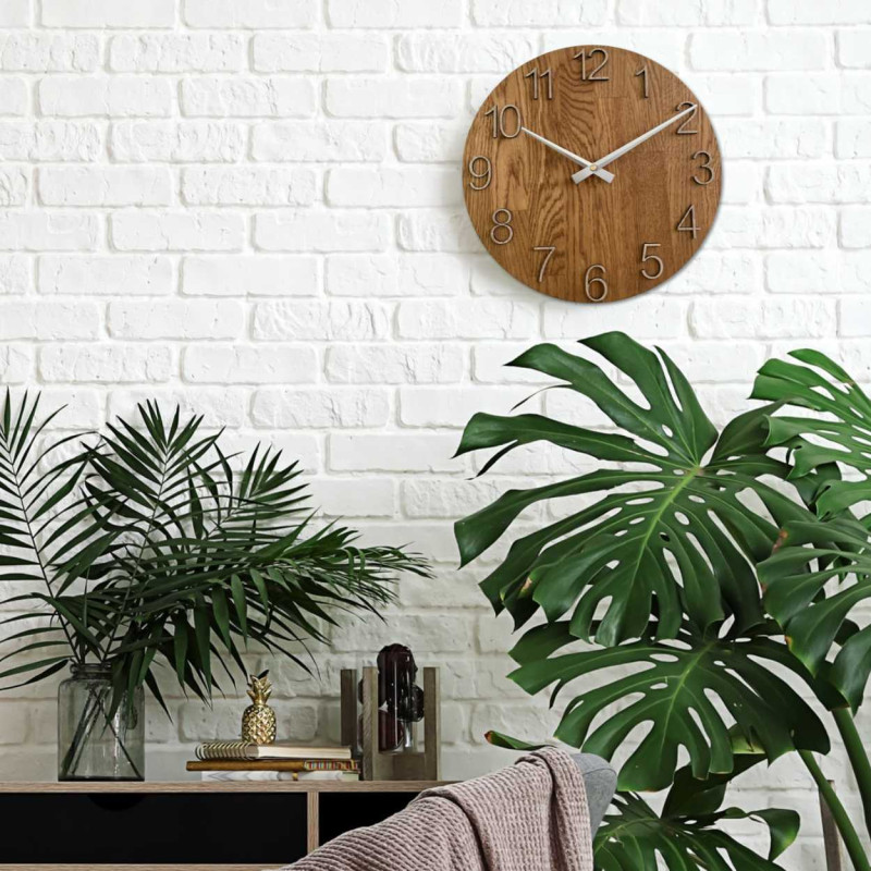 Round clock with a decorative cutout in the center and a delicate wood pattern.