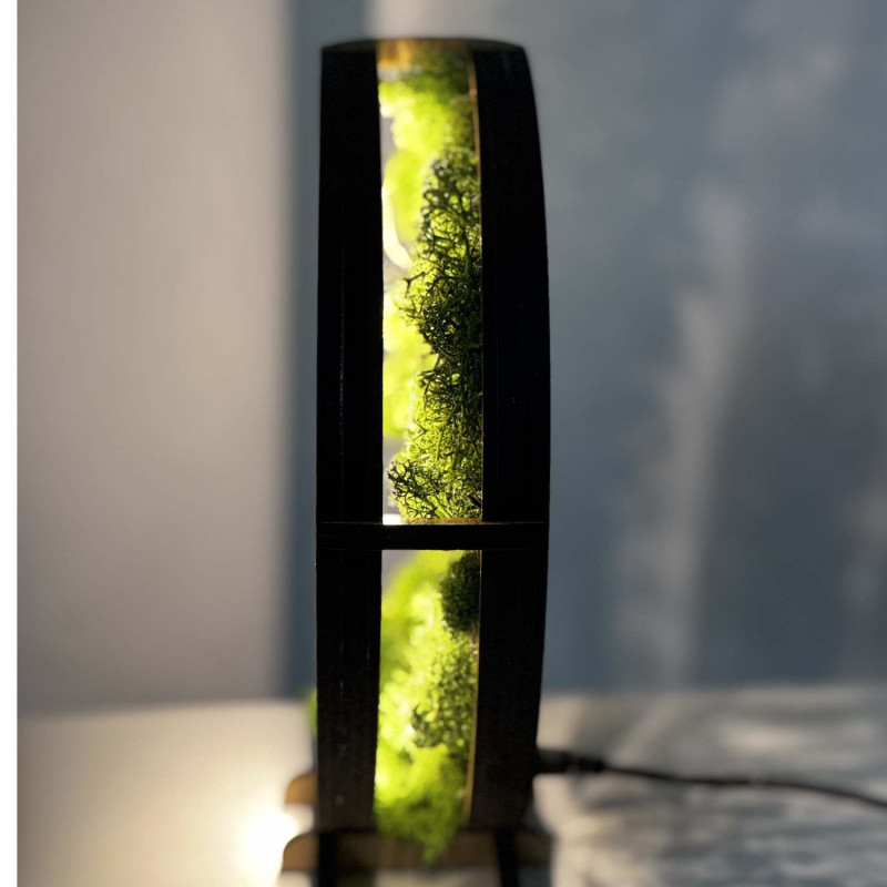 A close-up view of a backlit wooden Tree of Life surrounded by moss.