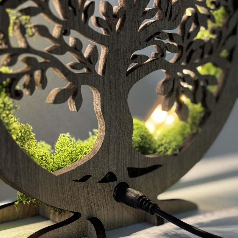A close-up view of a backlit wooden Tree of Life surrounded by moss.